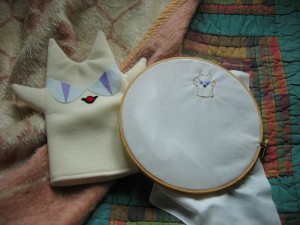 An official Beelzenef puppet next to a decidedly unofficial embroidered Beelzenef.